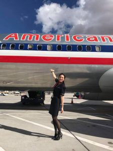 Flight attendant posing in front of American Airlines plane