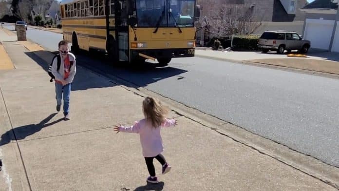 Girl runs to hug brother as he gets off school bus