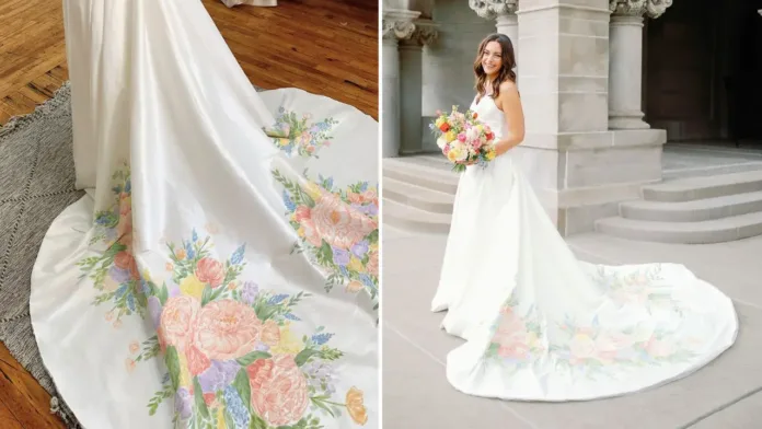 A close-up of a white wedding dress train adorned with a vibrant, hand-painted floral design in shades of pink, orange, purple, yellow, and green.