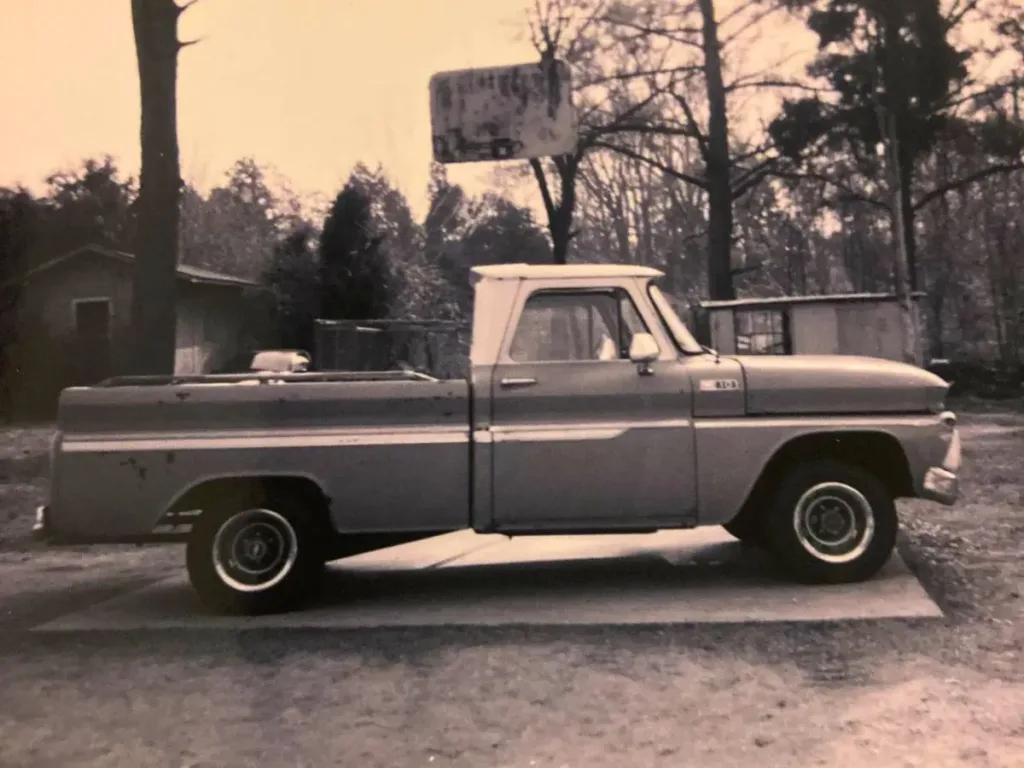 A vintage black and white photo of a 1965 Chevrolet C10 truck parked outdoors.
