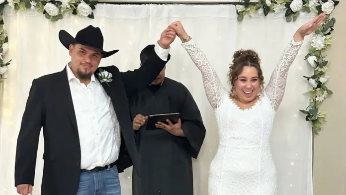 Jay and Carlos Perez hold hands in the air and smile proudly moments after being married in their living room.