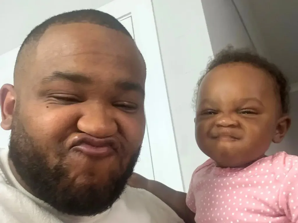 A playful selfie shows a father and his toddler daughter making matching humorous expressions at the camera