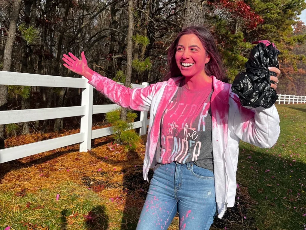 Woman celebrates while covered in pink powder after gender reveal cannon mishap