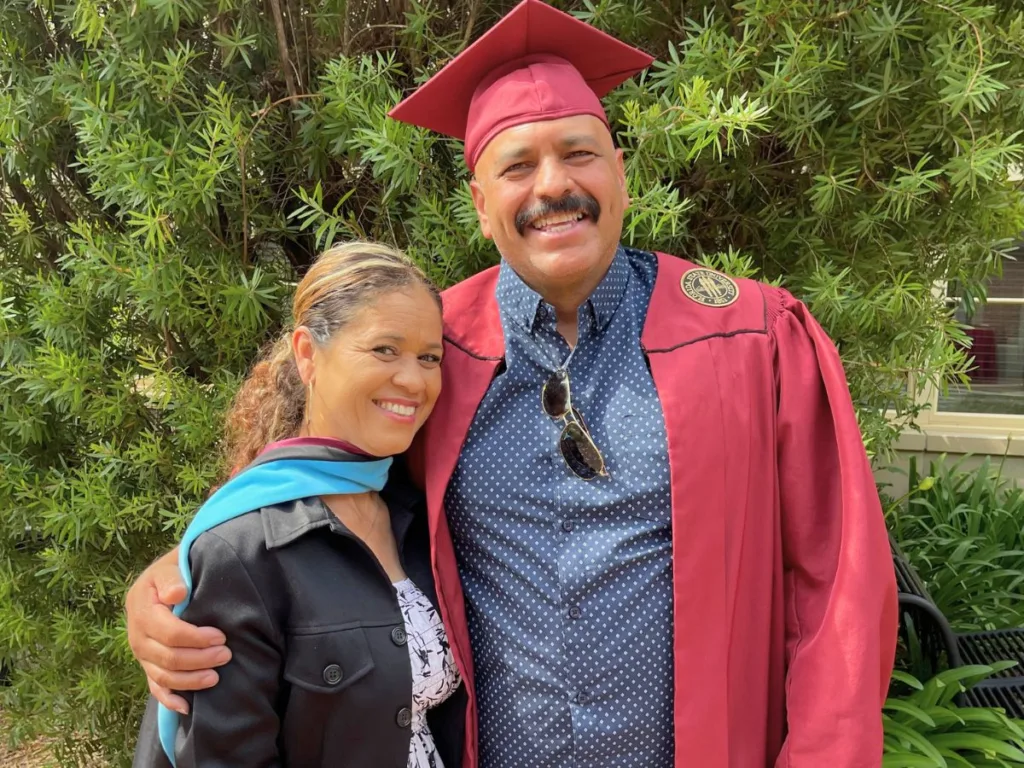 Martin Jr.'s father wears his son's graduation cap and gown while smiling with his wife, who wears the master's hood.