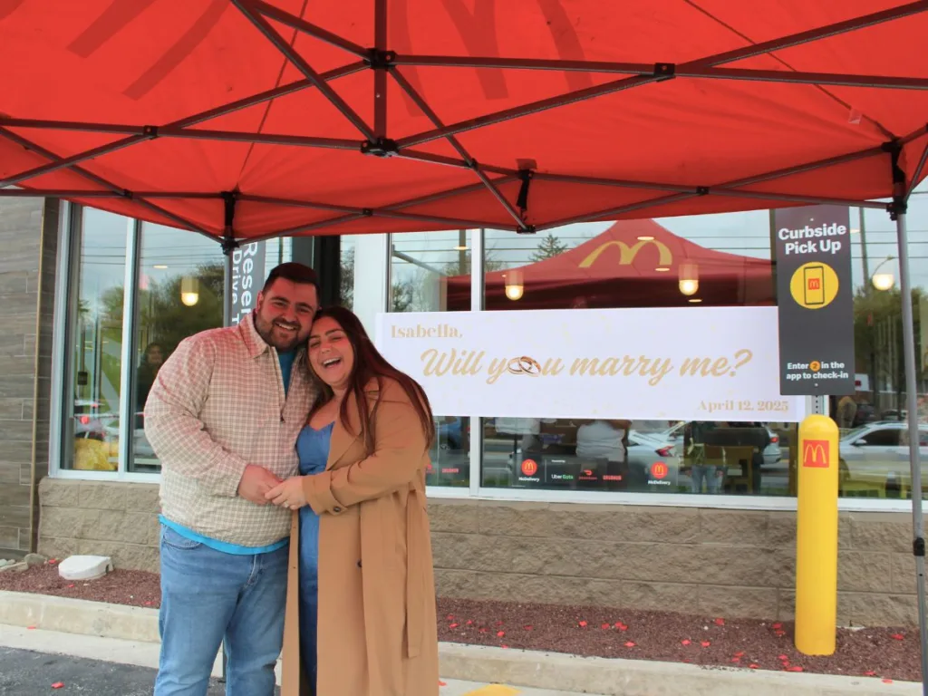 Happy couple smiling under McDonald’s tent after McDonald's proposal.