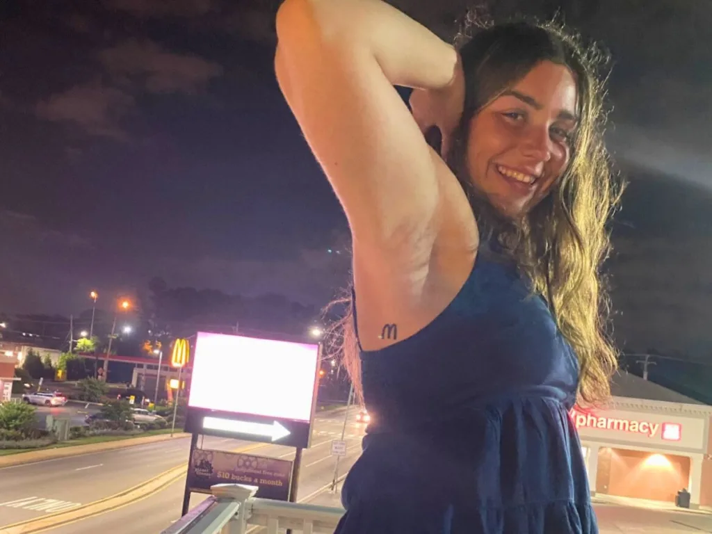 Woman showing off a small McDonald’s tattoo under her arm.