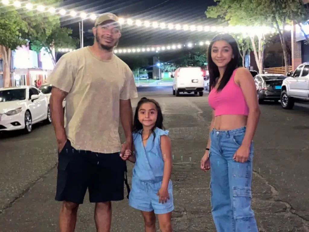 Lorenz Stefan standing outdoors on a city street at night, smiling with his two stepdaughters Jazelle and Aria