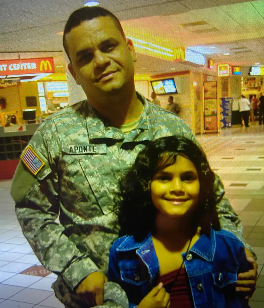 Army colonel Alvin Aponte Gonzalez with his daughter Ariana as a child, posing in a food court.