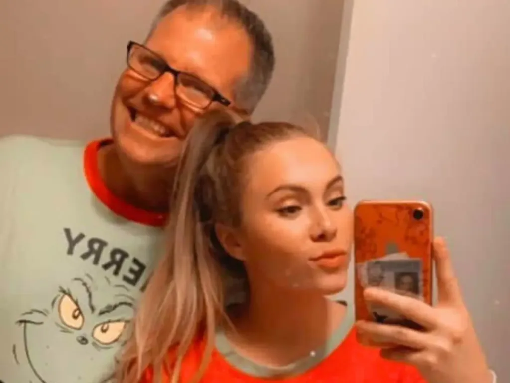 Stepdad and stepdaughter take a mirror selfie together wearing matching Grinch pajamas.