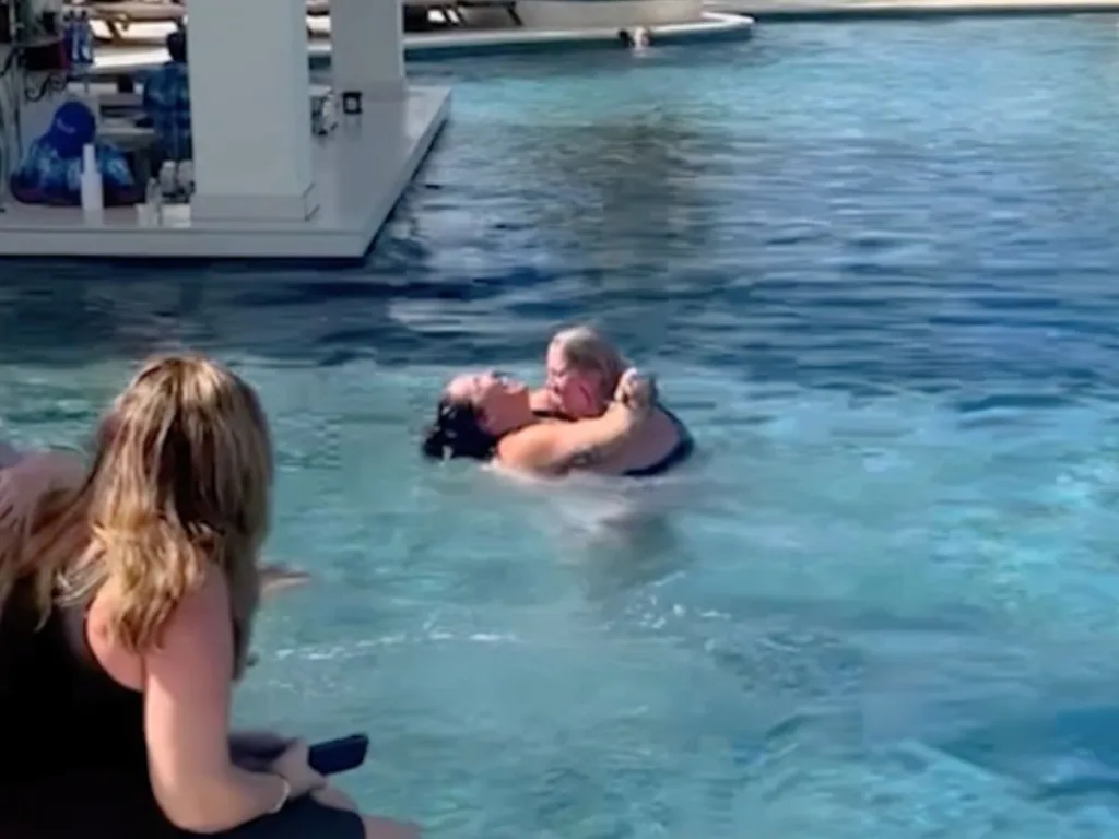 Trisha and Abby embracing in the pool as a friend watches from the side.