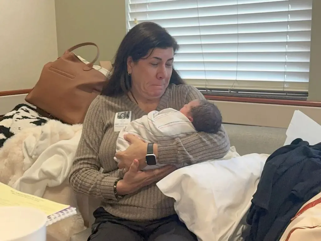 Natalie cradles newborn Monroe in her arms, tears of joy welling up as she holds her first grandchild for the first time.