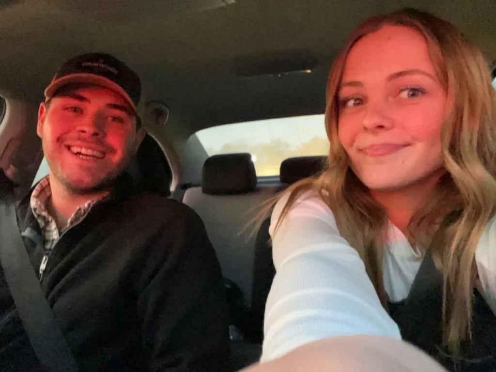 Smiling brother and sister take a selfie in a car.
