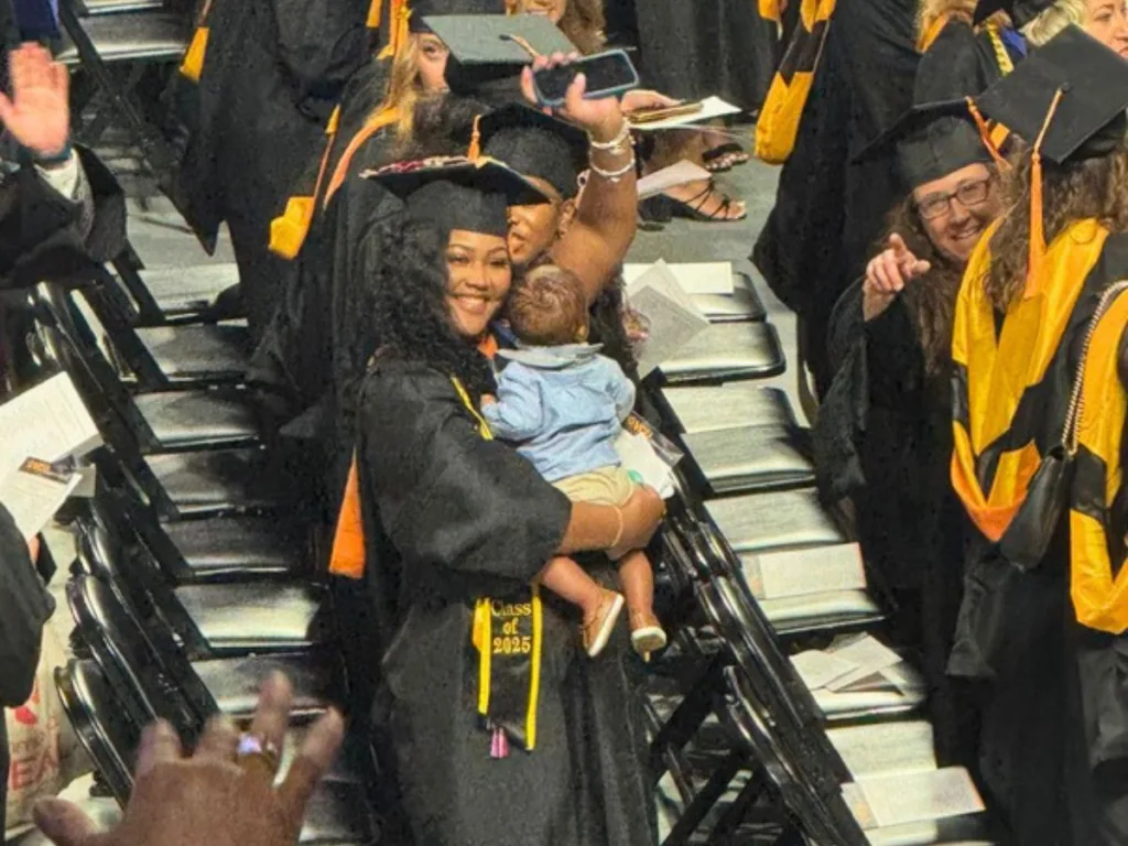 Jada Hargrove holds her baby while classmates celebrate during the graduation ceremony.