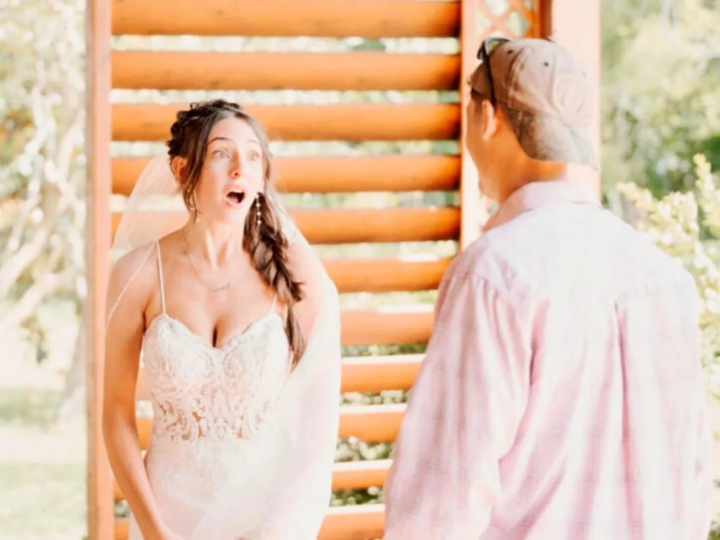 Bride looks shocked seeing someone during first look at wedding venue.