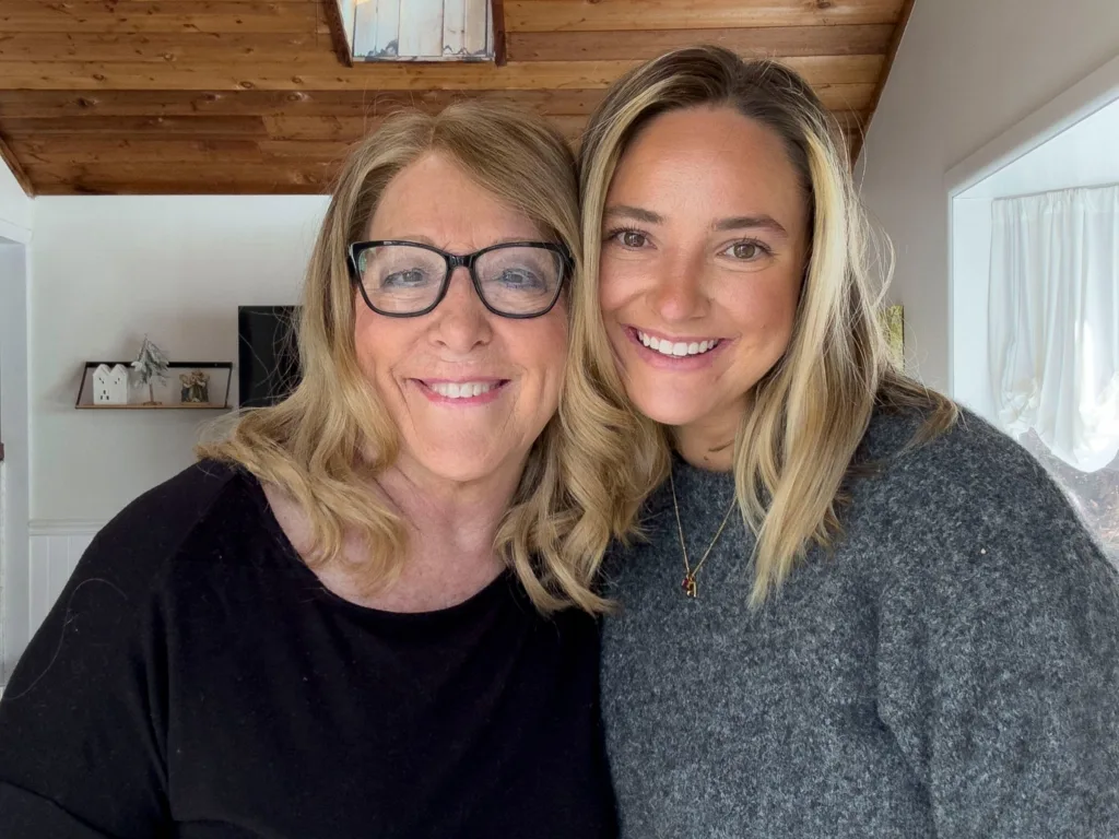 Teresa and Brooke smile for a close-up selfie indoors.