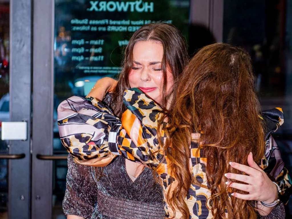 Kim hugs a friend tightly, eyes closed, during an emotional moment.