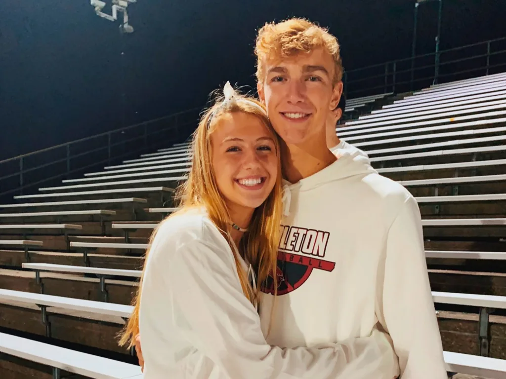 Parker and Sitori smiling and hugging in a photo taken on stadium bleachers.
