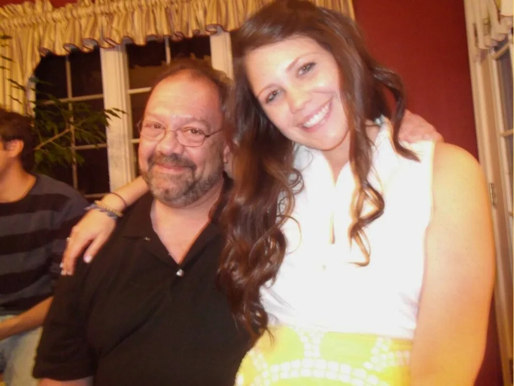 Lizzie Dean smiles with her father Ron in a casual photo, with her arm around his shoulders.