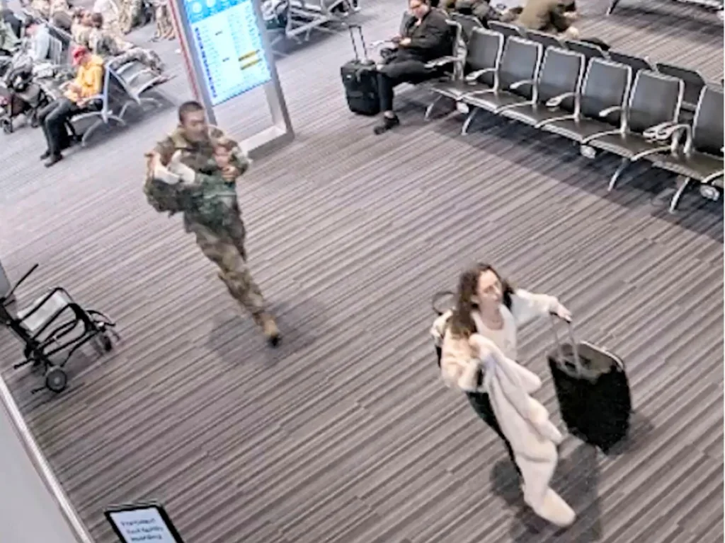 Tia pulls a suitcase through the airport while a soldier runs behind carrying River so the family can reach their gate in time.