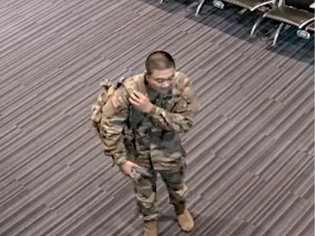 An unidentified soldier in uniform stands inside an airport terminal after helping a family rushing to catch a flight.