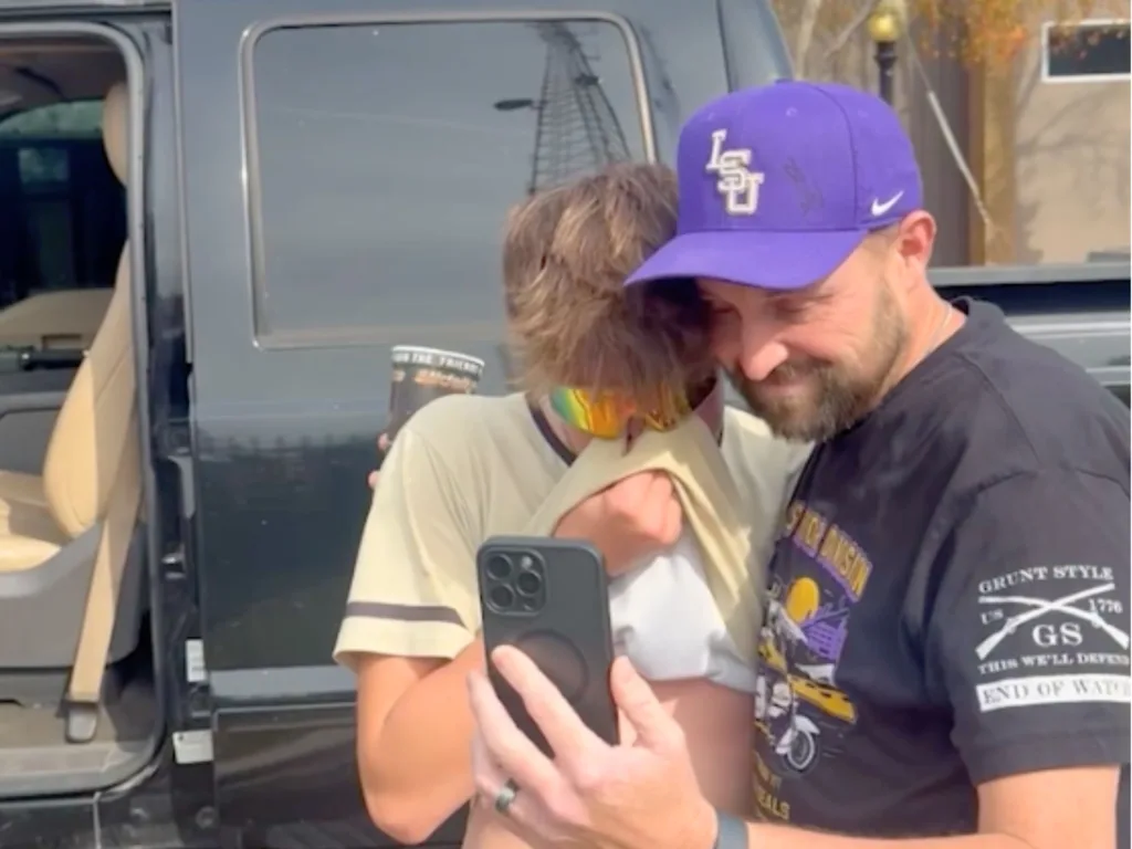 Levi wipes away tears while looking at a phone beside a family member after being surprised with his late father’s truck