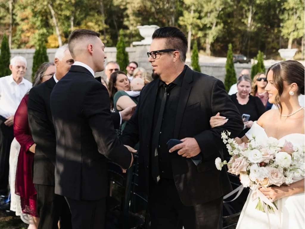Greg shakes hands with Alex at the altar while Madison smiles beside them holding her bouquet.