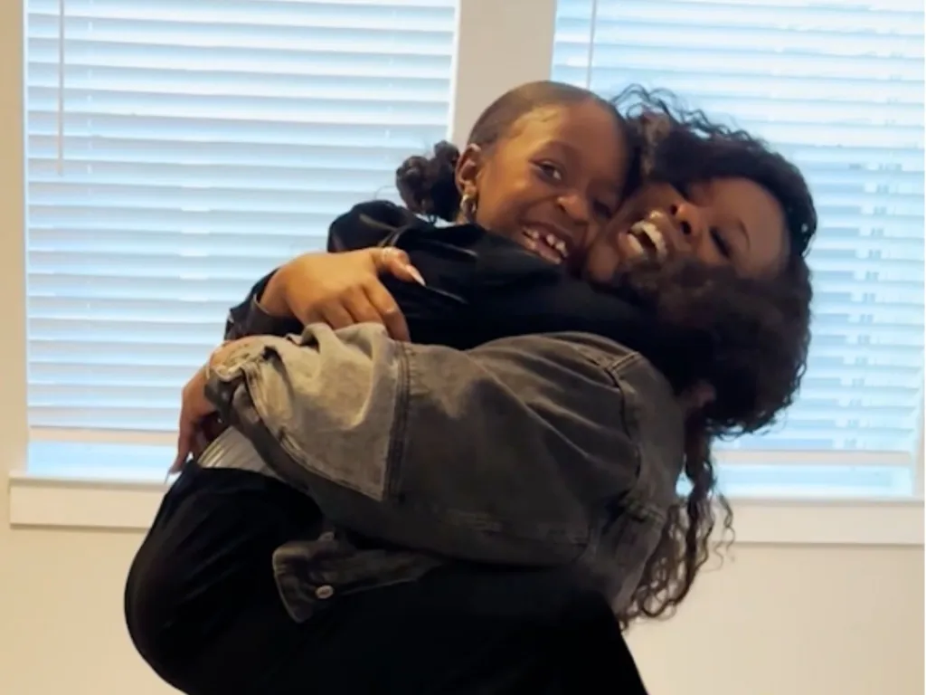 Mireya smiles as Marissa lifts her in a hug inside the empty house after revealing it is their new home.