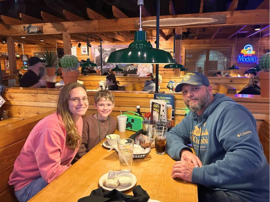 Amanda, Noah, and Chris sit together at a table inside Texas Roadhouse during Noah’s birthday visit