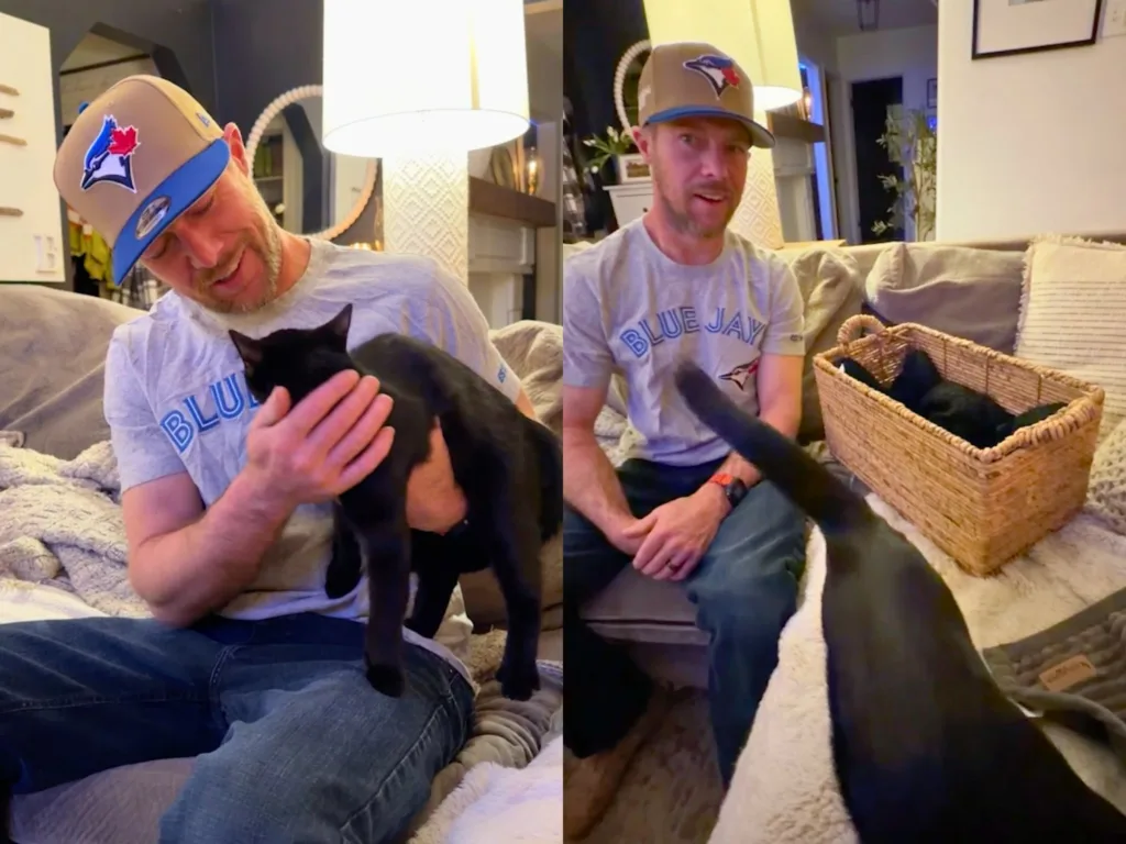 Adrian sitting with a black cat on the sofa