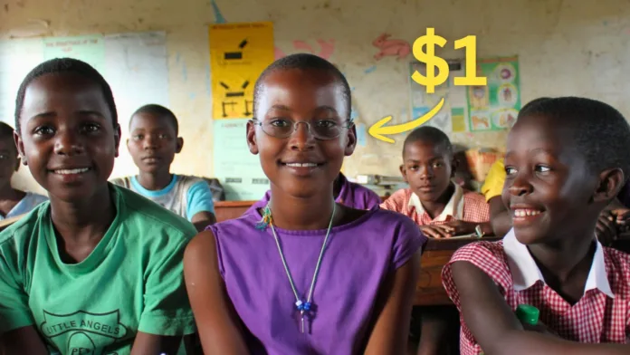 OneDollarGlasses1 A schoolgirl in a Ugandan classroom wearing One Dollar Glasses smiles between classmates, with a $1 callout pointing to her glasses.