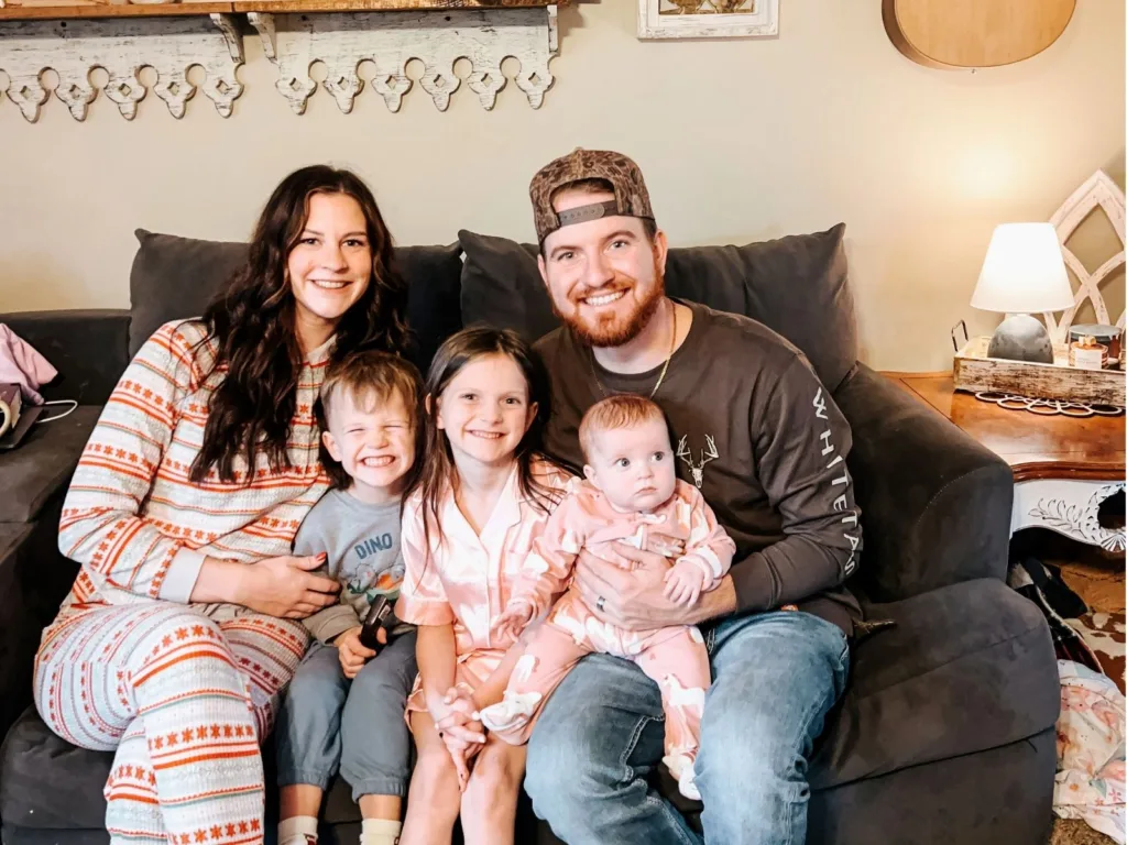 Skylar and her family sit together on a couch at home with their three children.