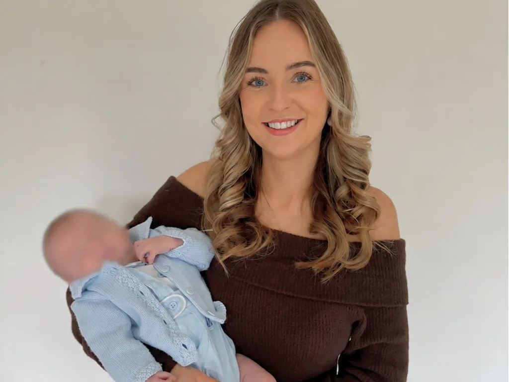Amy smiles while holding her baby son in a portrait photo.