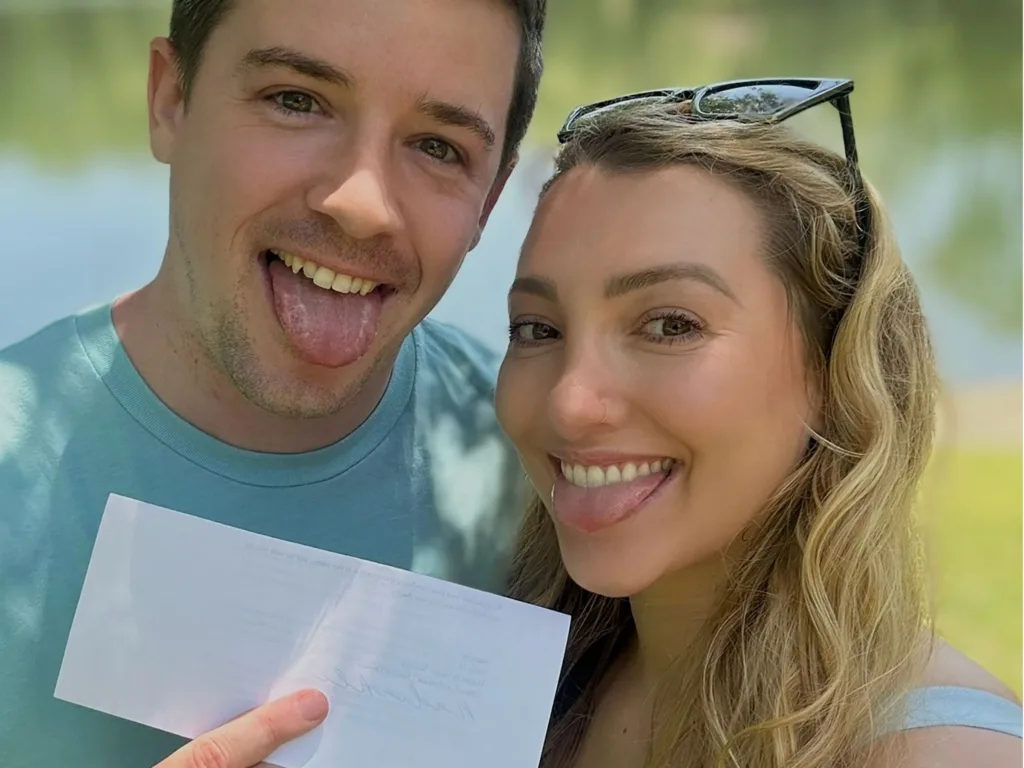 Matt and Heather smile while holding the fake letter after Heather surprised him with her pregnancy news.