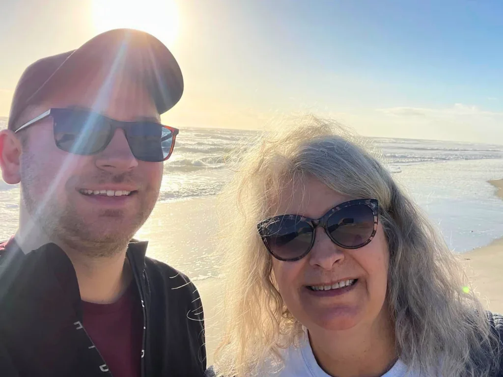 Eric takes a sunny beach selfie with his mom by the ocean.