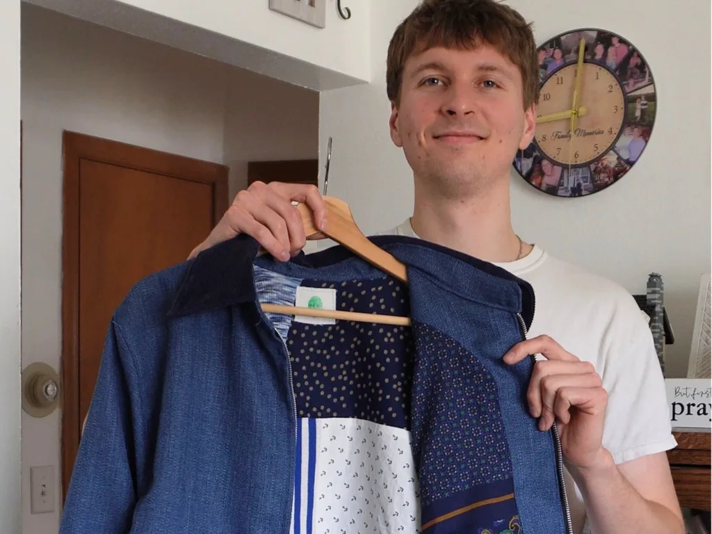 Mason holds up the blue jacket, showing the patchwork lining made from Eric’s mom’s clothes.