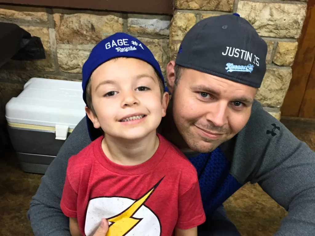 Gage smiles beside Justin in a childhood photo, with both wearing baseball caps.