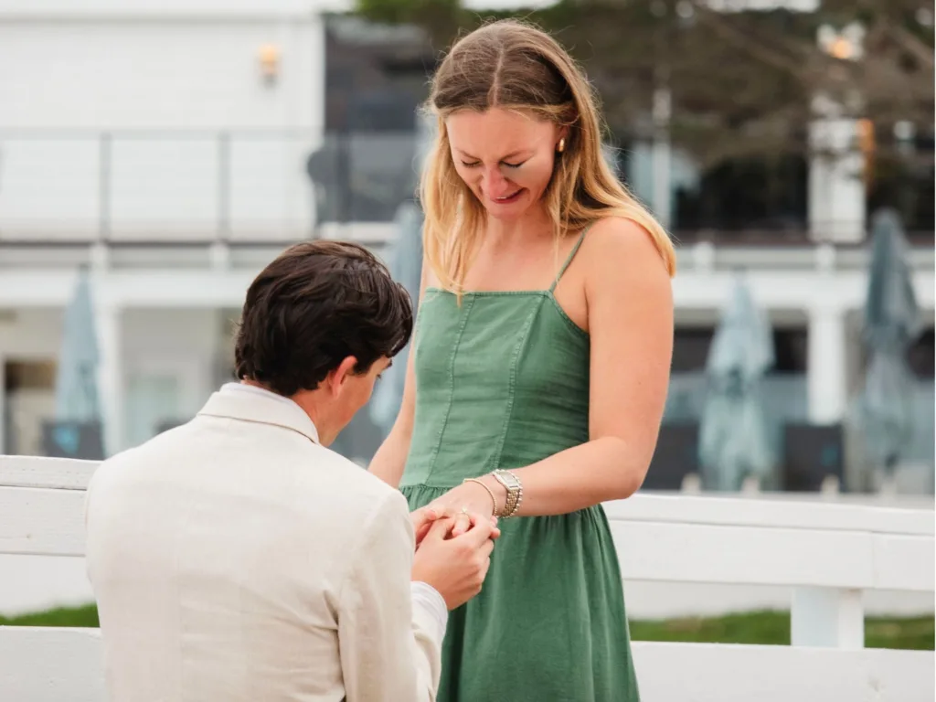 Mark gets down on one knee to propose to Jessica near the water at Pebble Beach after her unexpected golf ball injury.