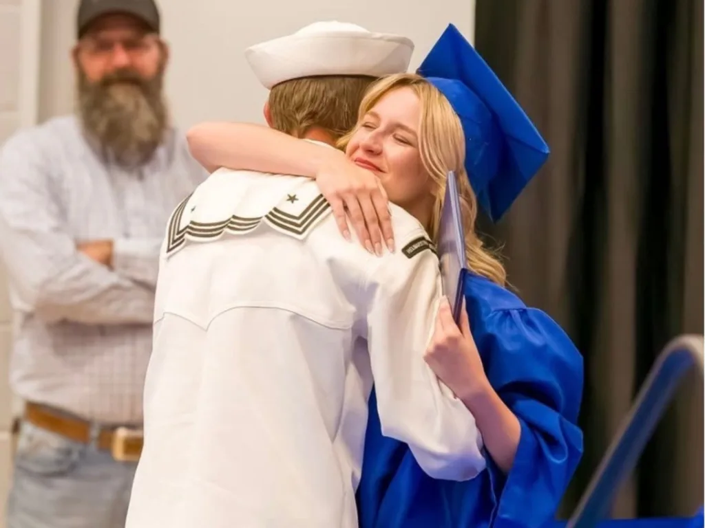 Sydnie hugs her Navy brother Skylar after he returned home to surprise her at her graduation ceremony.