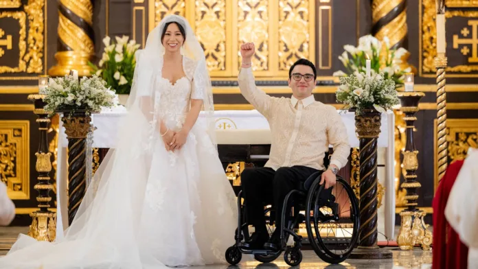 Andy sits in his wheelchair beside Michelle at the altar during their wedding ceremony in the Philippines.
