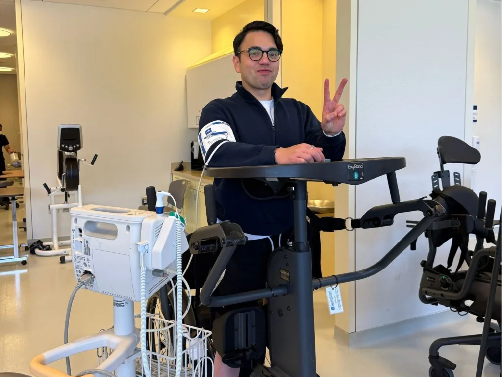 Andy stands upright in a rehabilitation standing frame during training before his wedding first dance surprise.