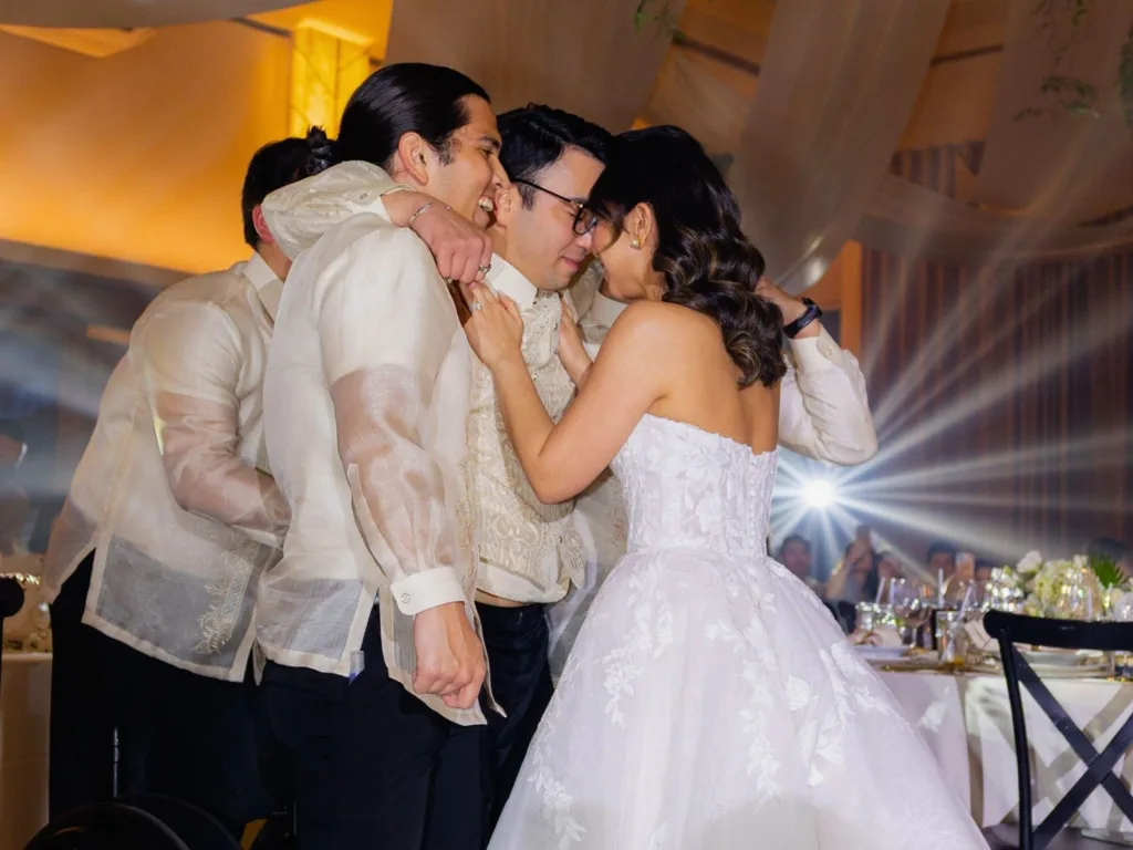Michelle embraces Andy as his groomsmen help support him during their first dance at the wedding reception.